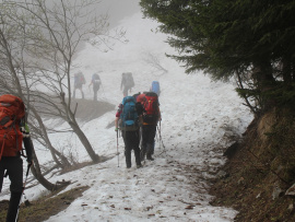 Des randonneurs dans la brume sur un sentier enneigé