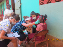 Des femmes avec un masque sanitaire examine la dentition d'une jeune fille