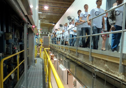 Étudiants circulant sur la passerelle devant la machine à papier expérimentale d’Innofibre.