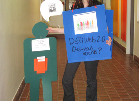 Une étudiante tenant une pancarte Défiweb - Êtes-vous inscrits?