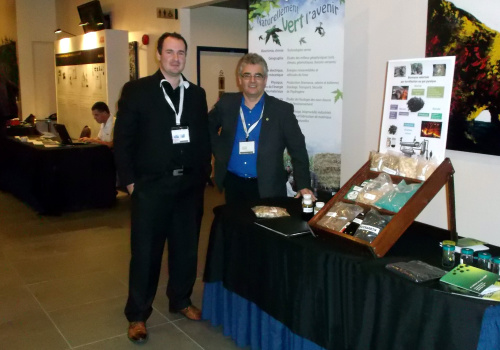 Les chercheurs Jean-Philippe Jacques et Jean Paradis devant le kiosque portant sur le bio charbon et autres produits valorisant les résidus cellulosiques.