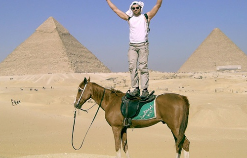 Guillaume Dulude debout sur un cheval devant des pyramides