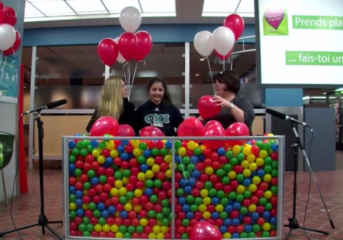 Trois femmes tiennent des ballons devant un bac de balles multicolores