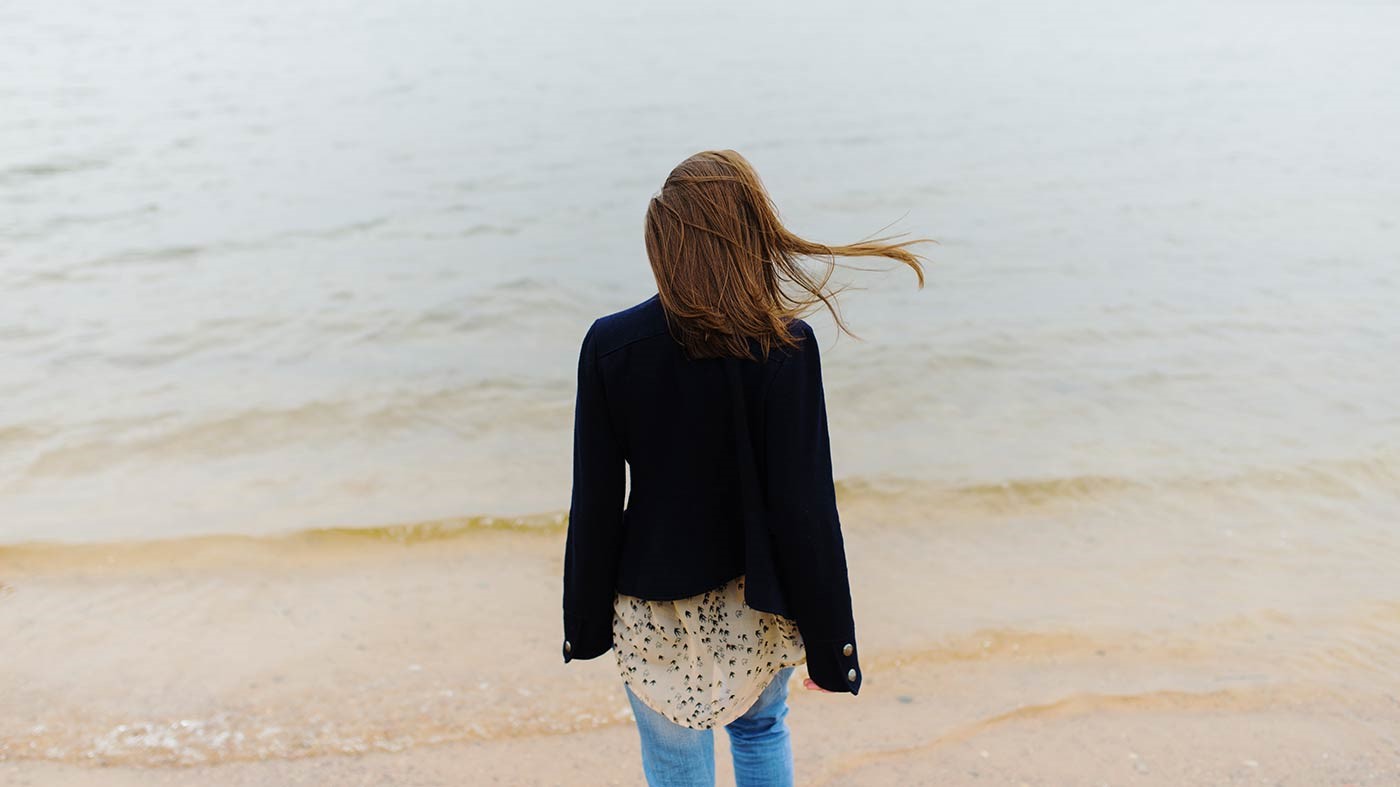 Photo de dos d'une jeune femme devant des vagues