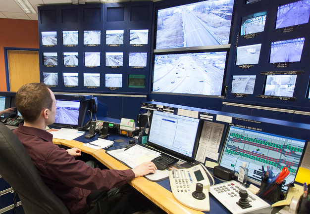 Un technicien en logistique de transport devant un mur d'écrans