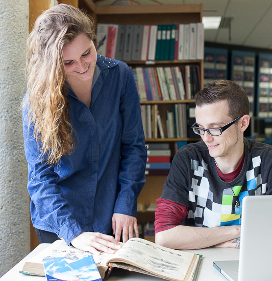 Deux étudiants regardent dans un livre à la biliothèque