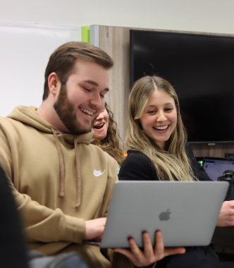 1 étudiant et 1 étudiante en gestion de commerces regardnt un ordinateur portable