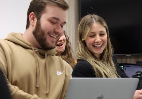 1 étudiant et 1 étudiante en gestion de commerces regardnt un ordinateur portable