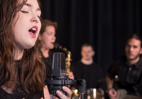 Une fille qui chante - en arrière-plan trois musiciens