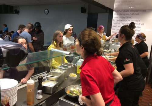 Le personnel de la cafétéria sert des repas aux étudiants