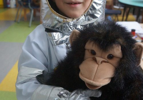 Un enfant vêtu d'un costume métallique tient un singe en peluche