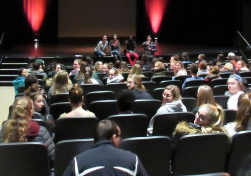 Étudiants assis dans la salle - 4 personnes assises devant sur la scène