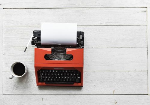 Photo d'une machine à écrire avec une feuille blanche et un café