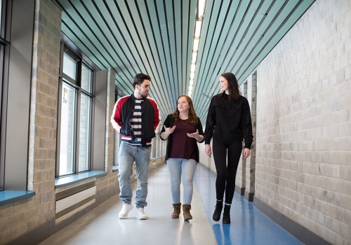 Trois étudiants marchent dans un corridor