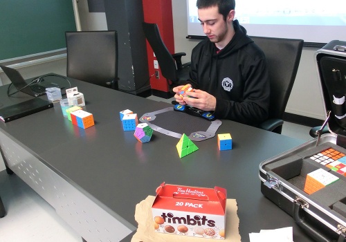 Simon Daoust, étudiant et membre du Club aux cubes, assis à une table et joue avec un cube