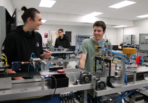 Trois étudiants dans un atelier de mécanique
