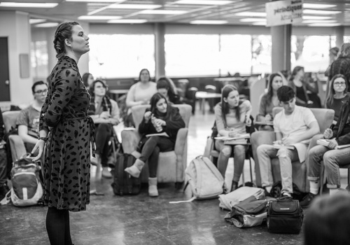 Un groupe d'étudiants dans la bibliothèque écoutent une conférencière