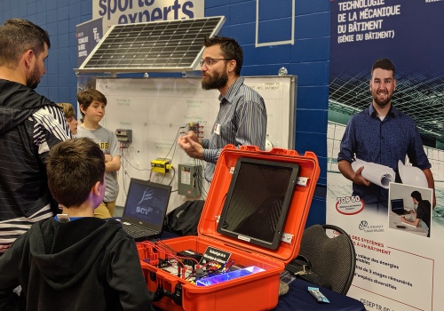 Au Salon des sciences 2019, un enseignant en Technologie de la mécanique du bâtiment parle à des visiteurs