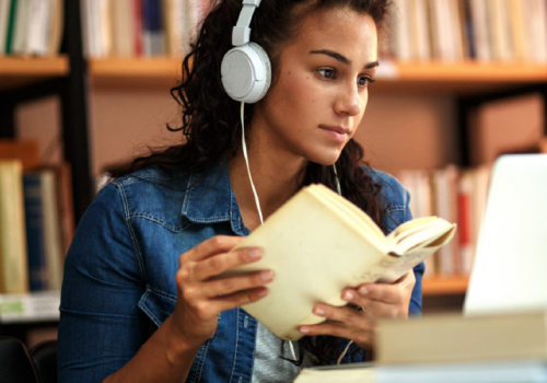 Une étudiante avec des écouteurs qui lit