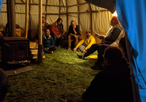 Groupe de personnes qui écoutent une histoire sous un abri extérieur