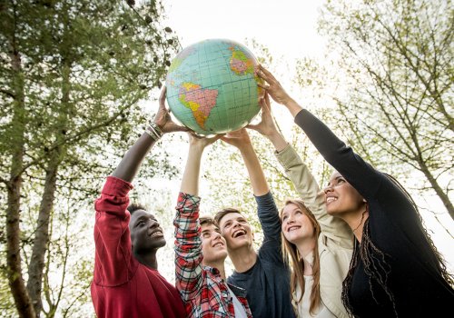Cinq jeunes tiennent ensemble un globe terrestre