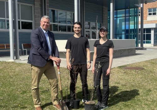 Le directeur général du cégep en compagnie de 2 étudiants sur le gazon pour faire la plantation d'arbres