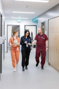 3 personnes en habit d'infirmière marchant dans un corridor