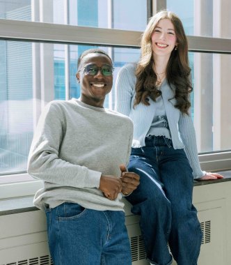 Un étudiant et une étudiante près d'une fenêtre