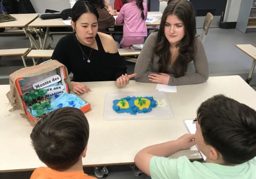 Deux étudiantes de Sciences humaines donnent des explications à des élèves du primaire